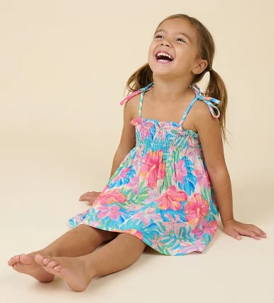 A single full-body photo of wearing the dress _ A child sitting with legs forward while leaning back slightly on both hands. Head tilted back with a joyful laugh_ carefree and playful. Photographed